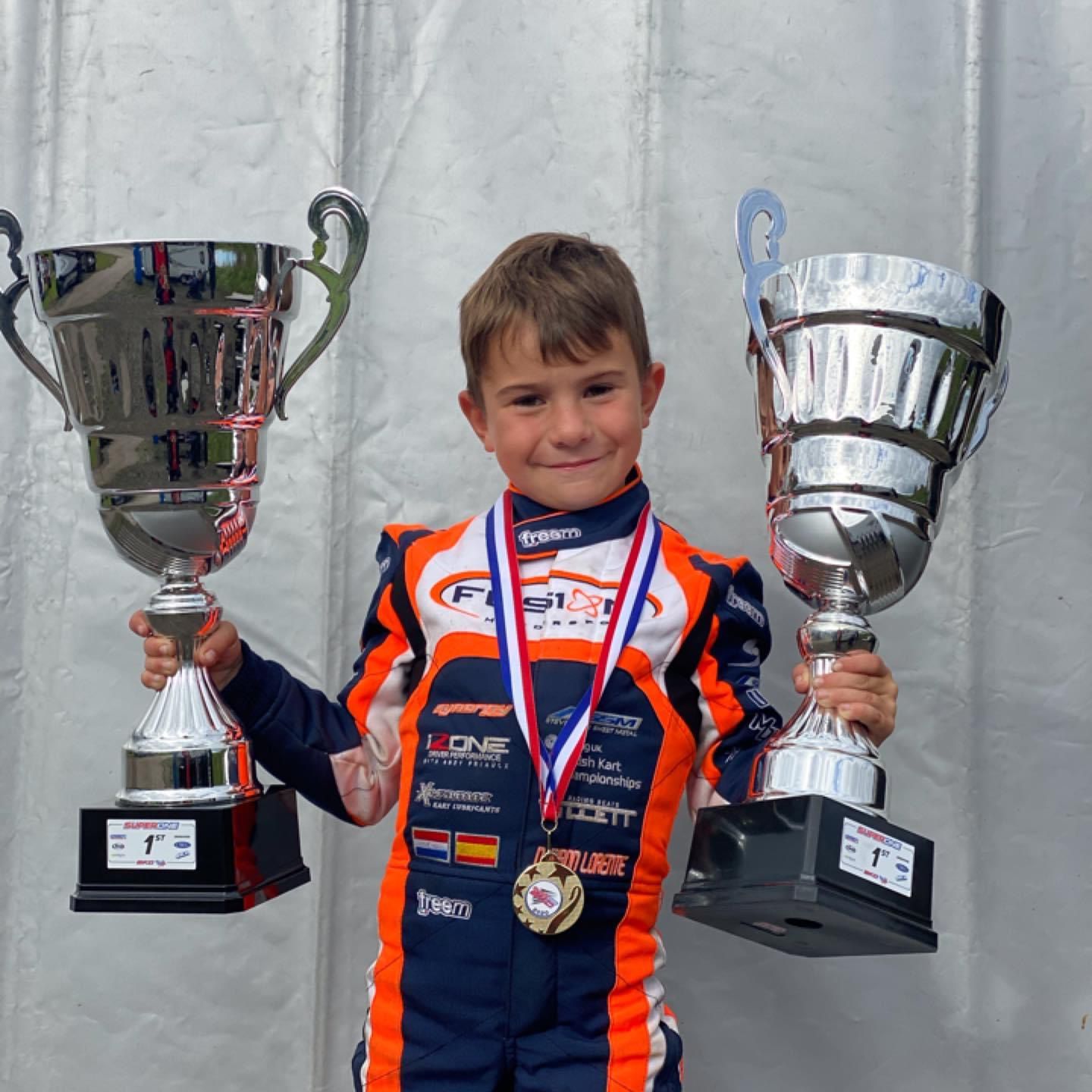 Daniel Miron de niño sosteniendo dos trofeos de gran tamaño