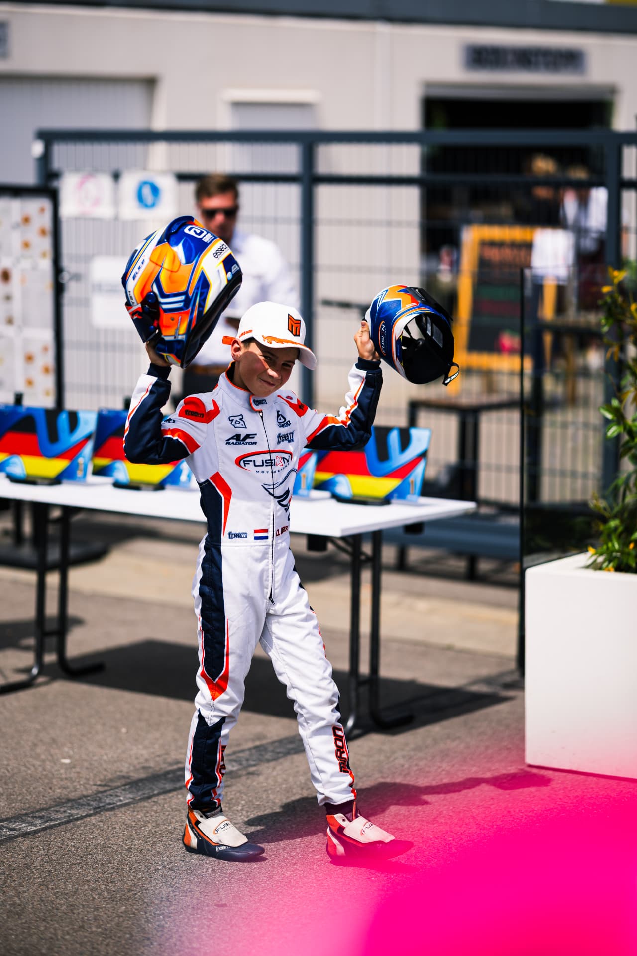 Daniel Miron de pie junto a su casco con el mono de carreras